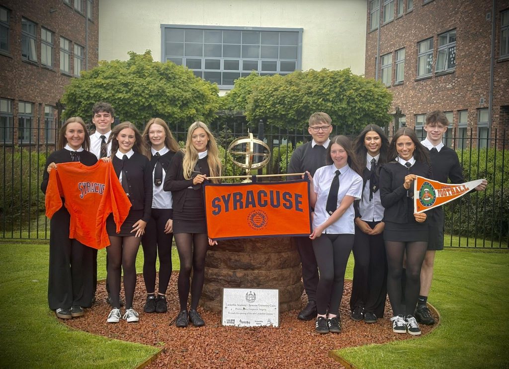 A group of students holding Syracuse pennants and sweatshirts